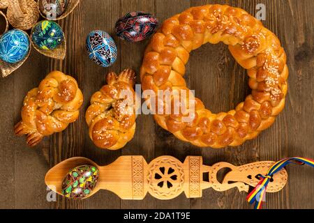 East European braided homemade bread with traditional painted eggs isolated on a wooden table. Stock Photo