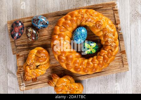 East European braided homemade bread with traditional painted eggs isolated on a wooden table. Stock Photo