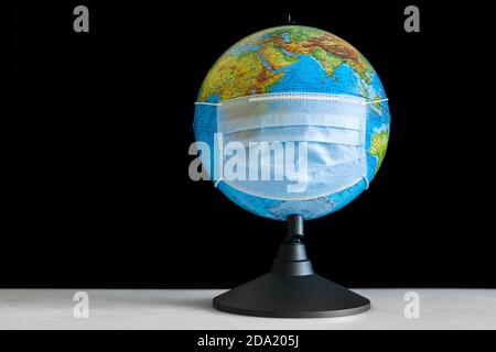 Earth globe in sterile medical mask at the table Stock Photo