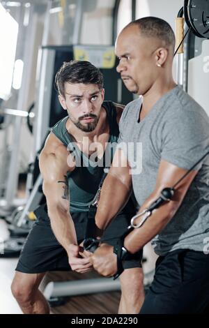 Fitness coach explaining mixed-race young man how to work out with