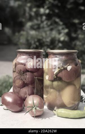 Canned tomatoes and peppers in glass jars. Stock Photo