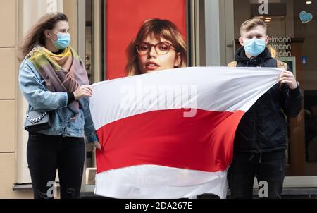 Peaceful protest supporting Belarus against ongoing repressions and call for free with young couple wearing masks and red and white flags of Belarus Stock Photo