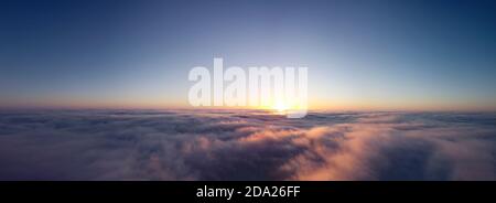 Thick fog and clear sky, orange morning sun illuminates the clouds. Panoramic shot of autumn morning fog Stock Photo