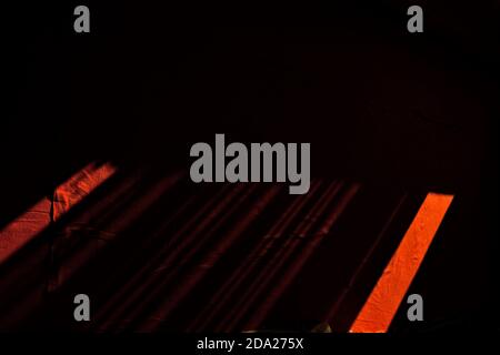 Black and red texture. Sunshine lights are coming and it creates linear texture on red carpet. Stock Photo