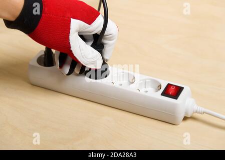 Closeup of an electrician plugging extension cords into each other. Mans hand plugging extension cord Stock Photo