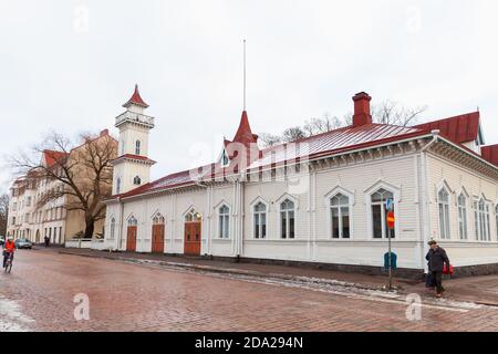 Kotka, Finland - December 14, 2014: Street view of Kotka town at winter day. Ordinary people walk the street near old wooden house with decorative tow Stock Photo