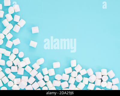 Marshmallows on blue background with copyspace. Flat lay or top view. Sweet ackground or texture with white colorful mini marshmallows. Stock Photo