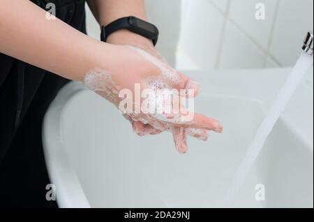 Soapy hands over sink in the bathroom. Hygiene & Cleaning Hands. Stock Photo