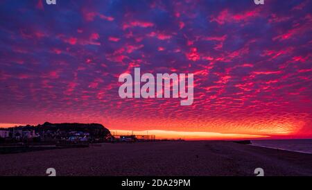 Dramatic November red dawn and mackerel clouds sky over Hastings beach front in east Sussex south east England Stock Photo