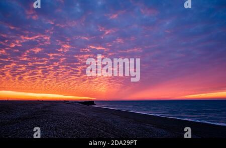 Dramatic red dawn mackerel sky over the beachfront of Hastings in east Sussex south east England Stock Photo
