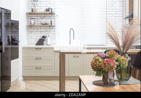 On a wooden kitchen table in a vase, a bouquet of hydrangeas as part of home decor. Stock Photo