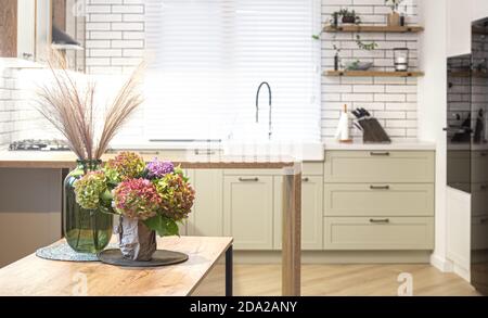 On a wooden kitchen table in a vase, a bouquet of hydrangeas as part of home decor. Stock Photo
