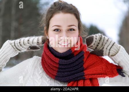 A young happy girl in a red knitted scarf and white mittens. Stock Photo