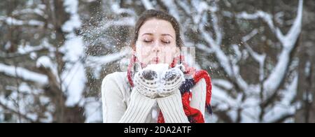 A young happy girl in a red knitted scarf and white mittens. Stock Photo