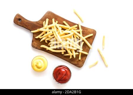 French fries on board with ketchup and cheese sauce isolated on white background. Homemade french fries. Stock Photo