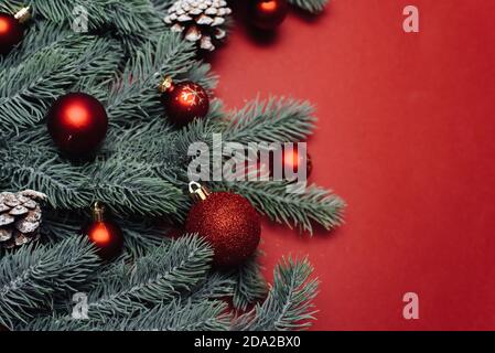 Space for text between Christmas tree branches with Christmas decorations and balls on a red background. Christmas composition. Happy New Year. Space for text. Stock Photo