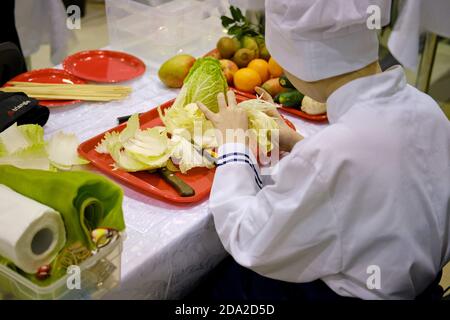 A man carves patterns on food to decorate a table with vegetables and fruits in the form of flowers Stock Photo