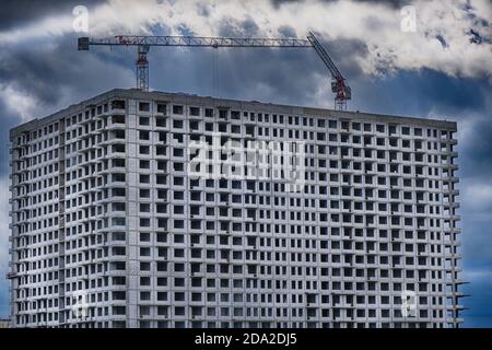 Multi-storey building and tower cranes close-up. Construction of the building against a stormy sky and clouds. Stock Photo