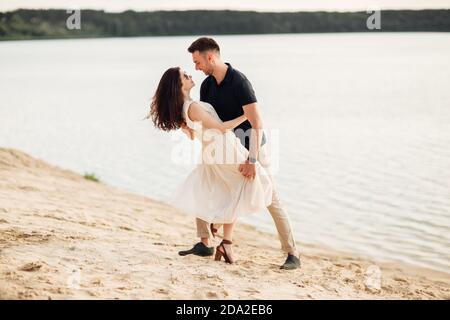 Young couple dancing at beach on sunny day Happy Romantic young Couple Enjoying Beautiful Sunset Walk on the Beach. Stock Photo