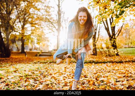 Positive afro hair woman with beautiful smile wearing sky blue laughing in autumn park on sunny day Stock Photo