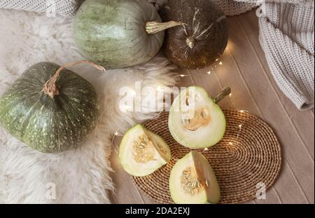 Autumn still life of pumpkins, pumpkin pieces and garlands in the interior of the room. Autumn mood at home close up. Stock Photo
