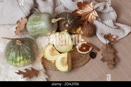 Composition of pumpkins, pumpkin pieces, autumn leaves, garlands on the background of the home interior close up. Stock Photo