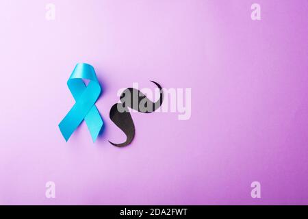 Black mustache paper and light blue ribbon, studio shot isolated on purple background, Prostate cancer awareness month, Fathers day, minimal November Stock Photo