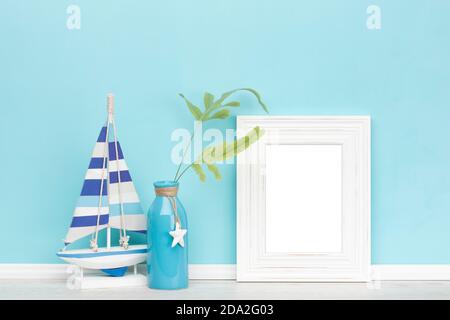 Background mockup template with shabby chic, vintage rustic white blank vertical picture frame, decorated vase with fern leaves in front of aqua color Stock Photo