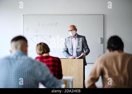 Young students with teacher studying at desks at college or university, coronavirus concept. Stock Photo