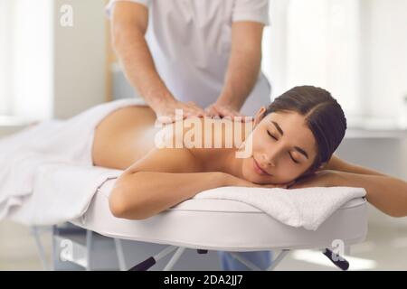 Young male osteopath doing professional back massage for woman in medical center. Stock Photo