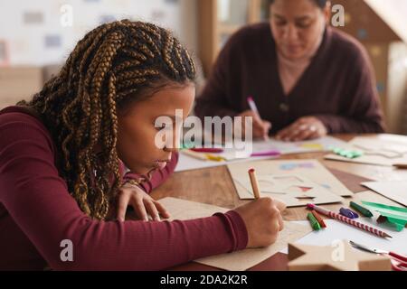 Side view portrait of teenage African-American girl drawing while enjoying art and craft class in school, copy space Stock Photo