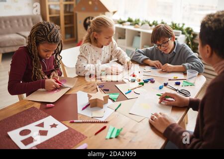 Multi-ethnic group of children making handmade Christmas cards together while enjoying art and craft class, copy space Stock Photo