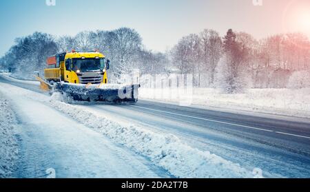 Snow plow truck clearing snowy road after snowstorm. Stock Photo