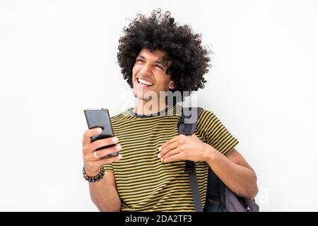 Portrait smiling young man with bag holding mobile phone by white background Stock Photo