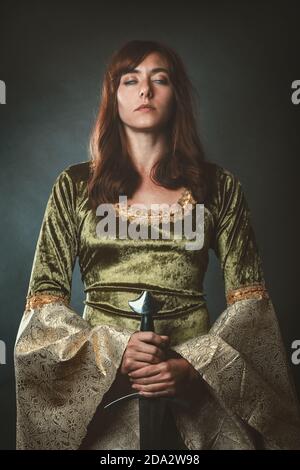 Medieval queen with sword and eyes closed. Red haired woman Stock Photo