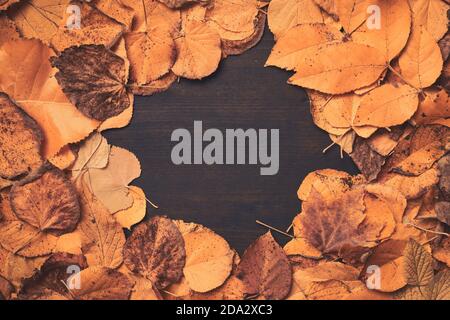 Creative autumn dry leaves background with copy space, flat lay top view of rustic wooden table with fall season deciduous foliage Stock Photo