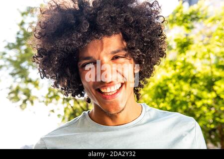 Close up portrait smiling handsome young man with afro hair outdoors Stock Photo