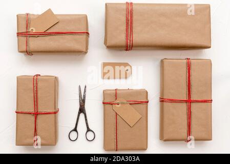 Christmas gift boxes wrapped in craft paper over white background prepared for celebrating festive holiday season Stock Photo