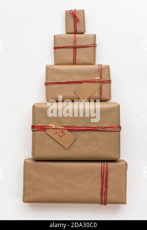 Christmas gift boxes wrapped in craft paper forming a Christmas tree figure on white background Stock Photo