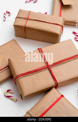 Christmas gift boxes wrapped in craft paper with red string and candy canes on a white background Stock Photo