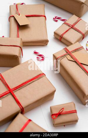 Christmas gift boxes wrapped in craft paper with red string and candy canes on a white background Stock Photo