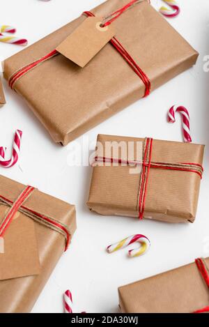 Christmas gift boxes wrapped in craft paper with red string and candy canes on a white background Stock Photo