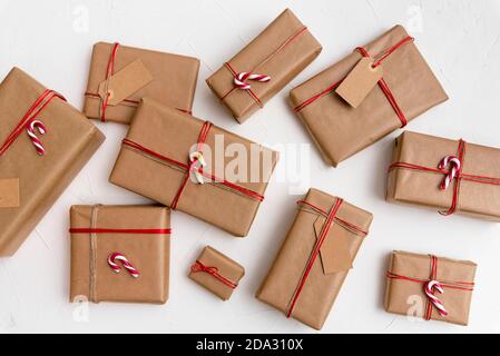 Christmas gift boxes wrapped in craft paper with red string and candy canes on a white background Stock Photo