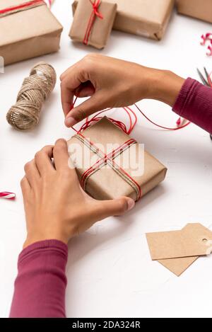 Female's hands wrapping Christmas gift boxes decorated with kraft paper Stock Photo