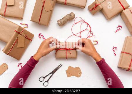Female's hands wrapping Christmas gift boxes decorated with kraft paper Stock Photo