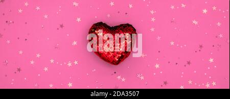 Christmas or Valentines composition made from glowing red heart decoration and glitter on pink surface. Merry christmas and happy 2021 New Year, Happy Stock Photo