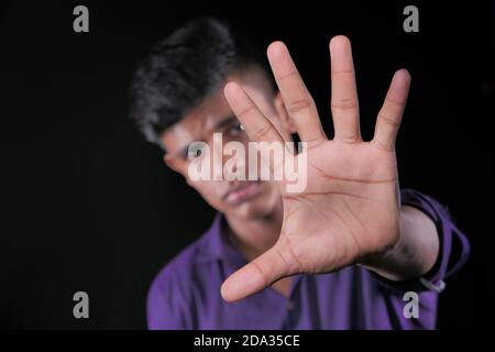young man show stop sigh isolated in black  Stock Photo