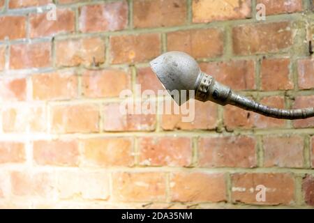 Old and rusty vintage industrial lamp shedding light on a red brick wall Stock Photo