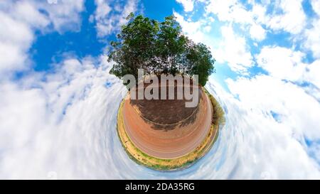 Small planet with trees, white clouds and soft blue sky. Green 360 Tiny planet of green grass ecology concept. Stock Photo