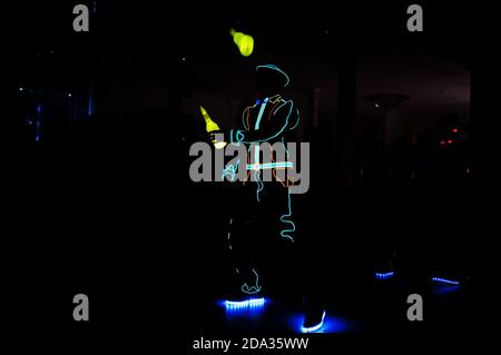 Professional barman and led light show. Silhouette of modern bartender shaking drink at night cocktail bar. Stock Photo